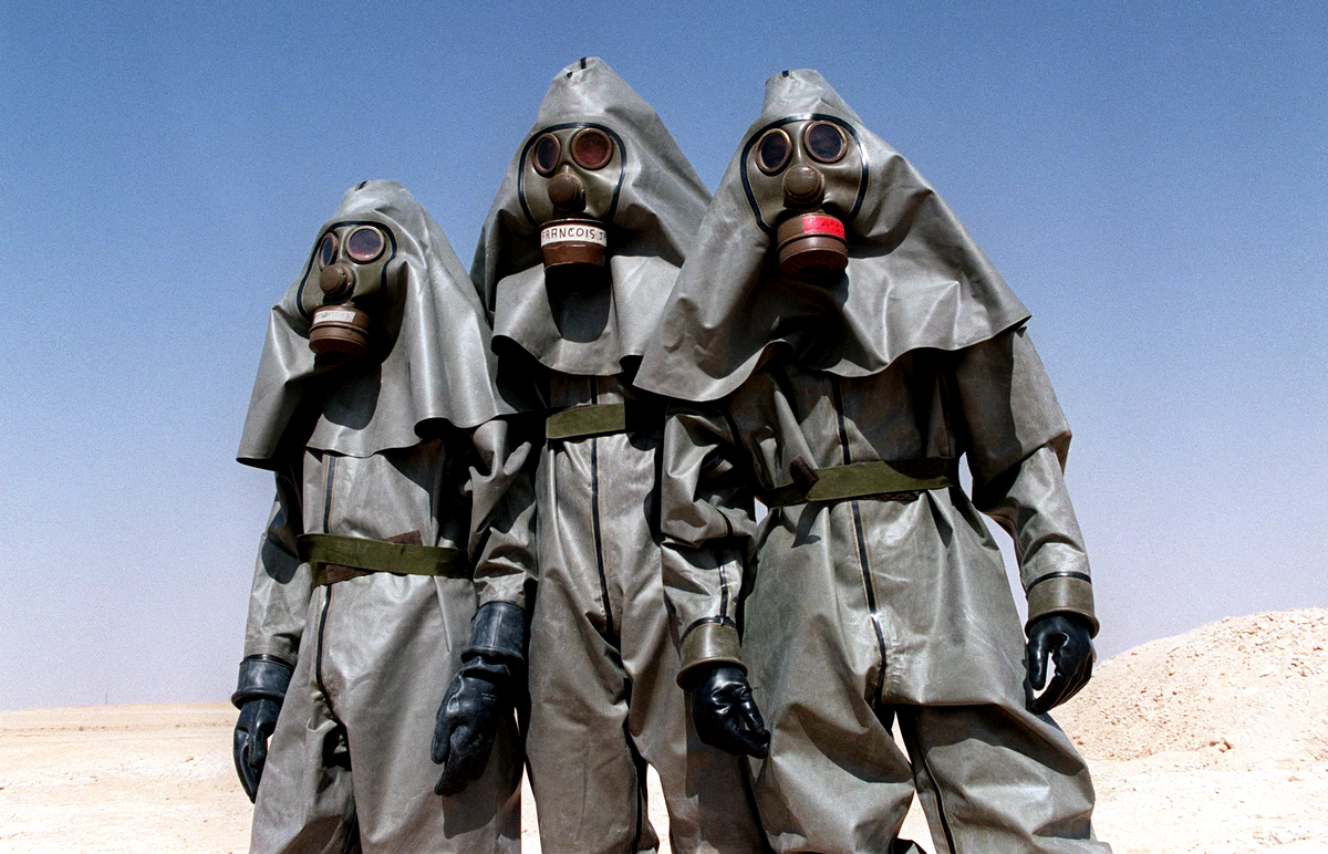 Three men wearing proctive chemical suits.